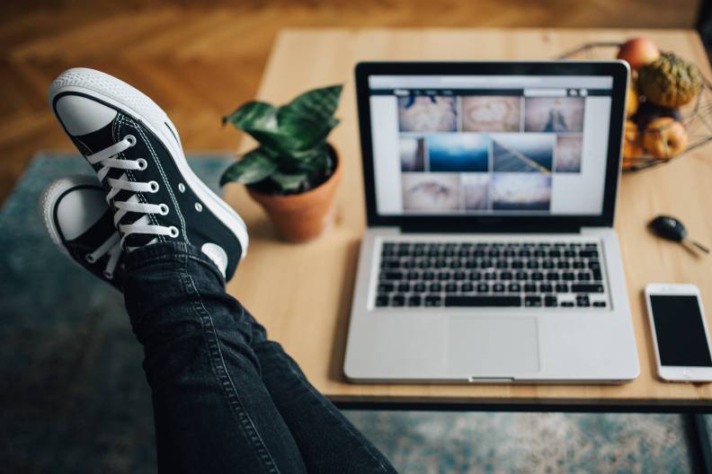 kaboompics_Woman in ripped jeans and black sneakers with a silver laptop on a wooden table.jpg