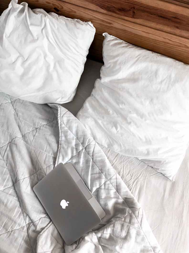 macbook on a messy bed